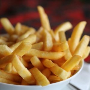 Delicious crispy golden french fries served in a white bowl, perfect for a tasty snack.